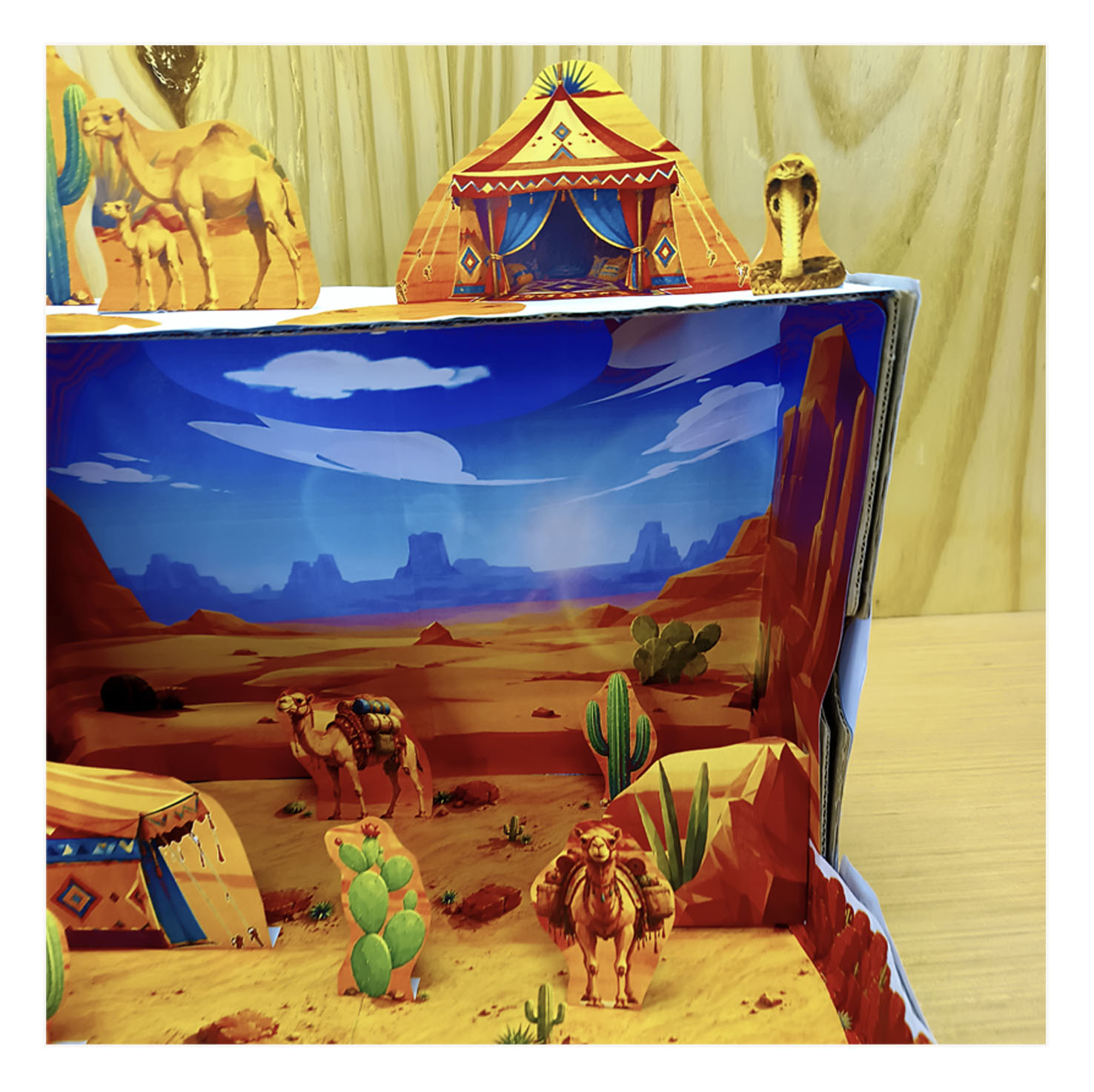 Side view of a desert habitat diorama with camels, cactus, tent, rocky landscape and extra cutout pieces above the backdrop