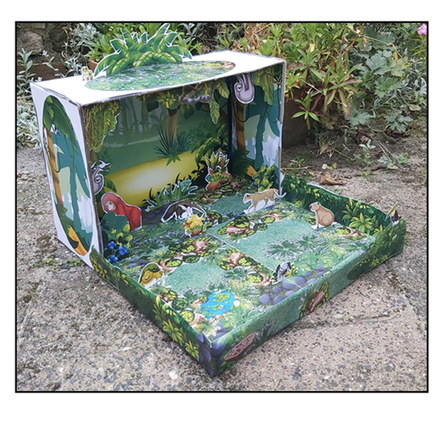Three-dimensional rainforest habitat diorama viewed from an angle with tropical plants and freestanding rainforest animals