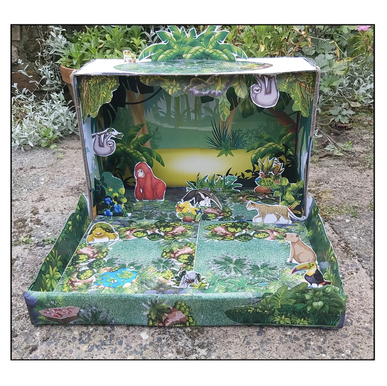Completed rainforest habitat diorama with tropical animals, plants and layered jungle scenery