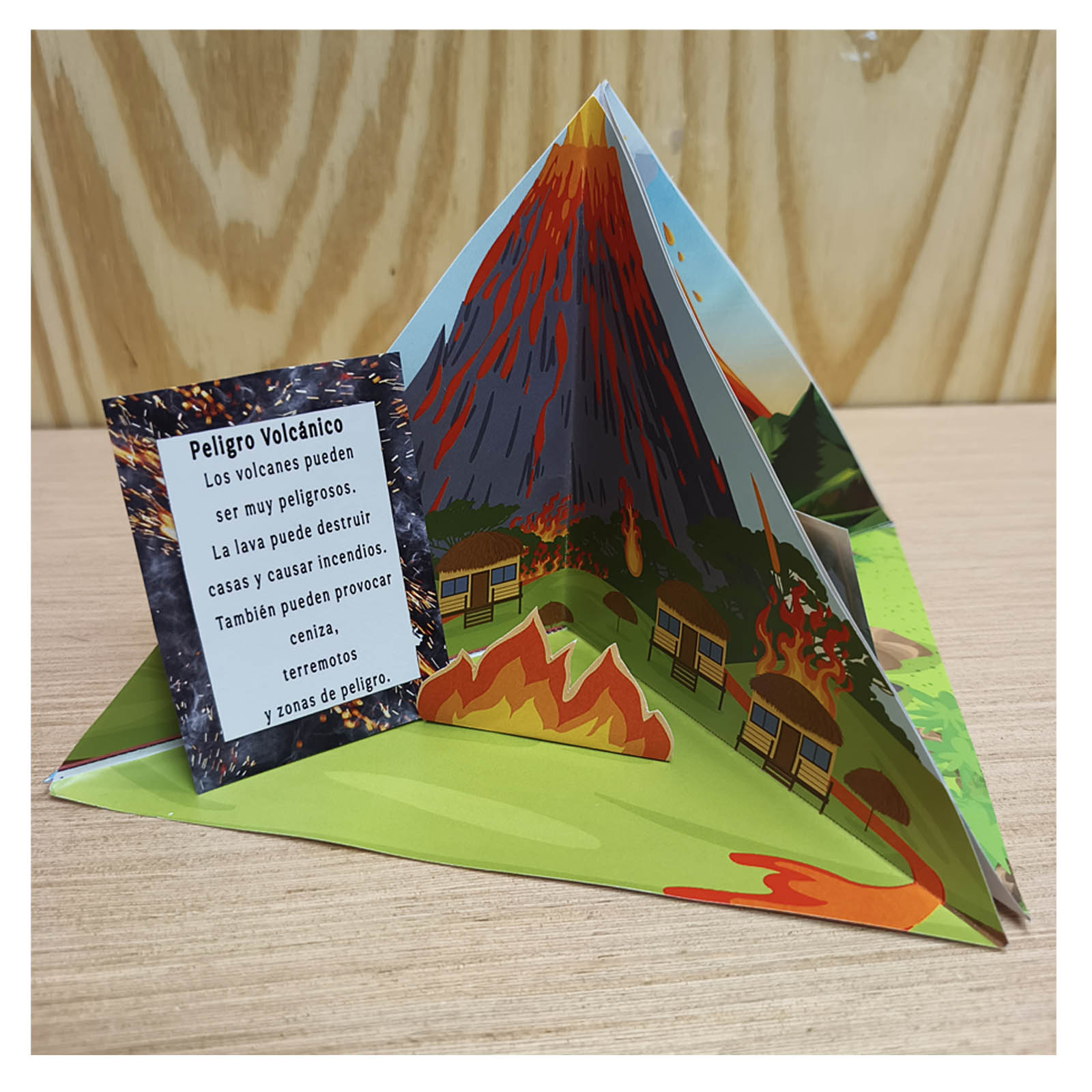 Assembled 3D paper volcano model for a school project, showing joined triangular sections with an island scene and numbered cross section